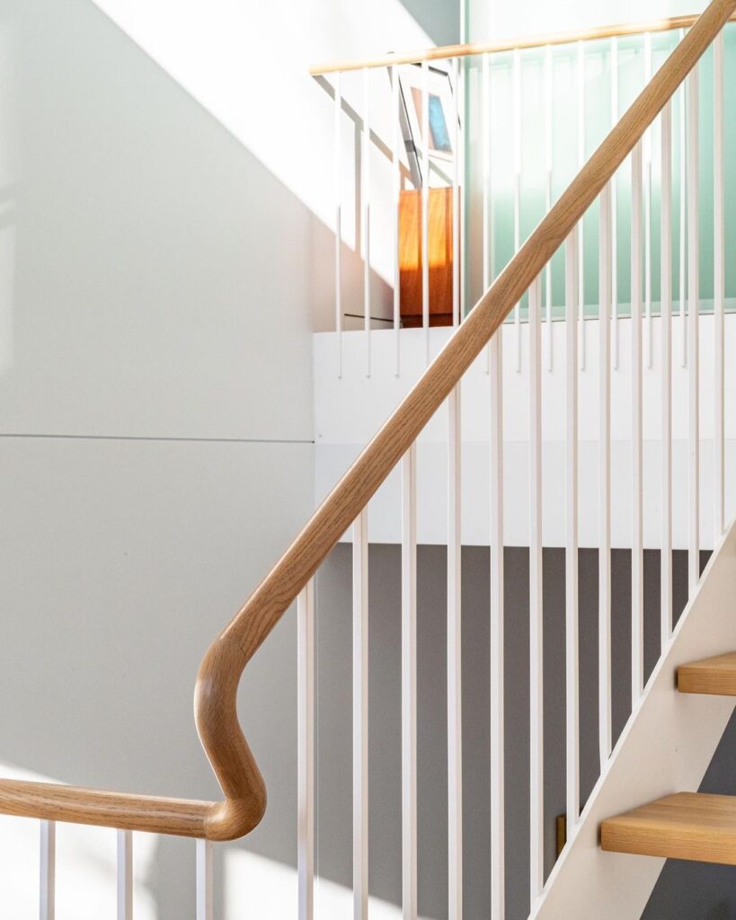 Light wood handrails on white metal balusters in a bright, modern home.