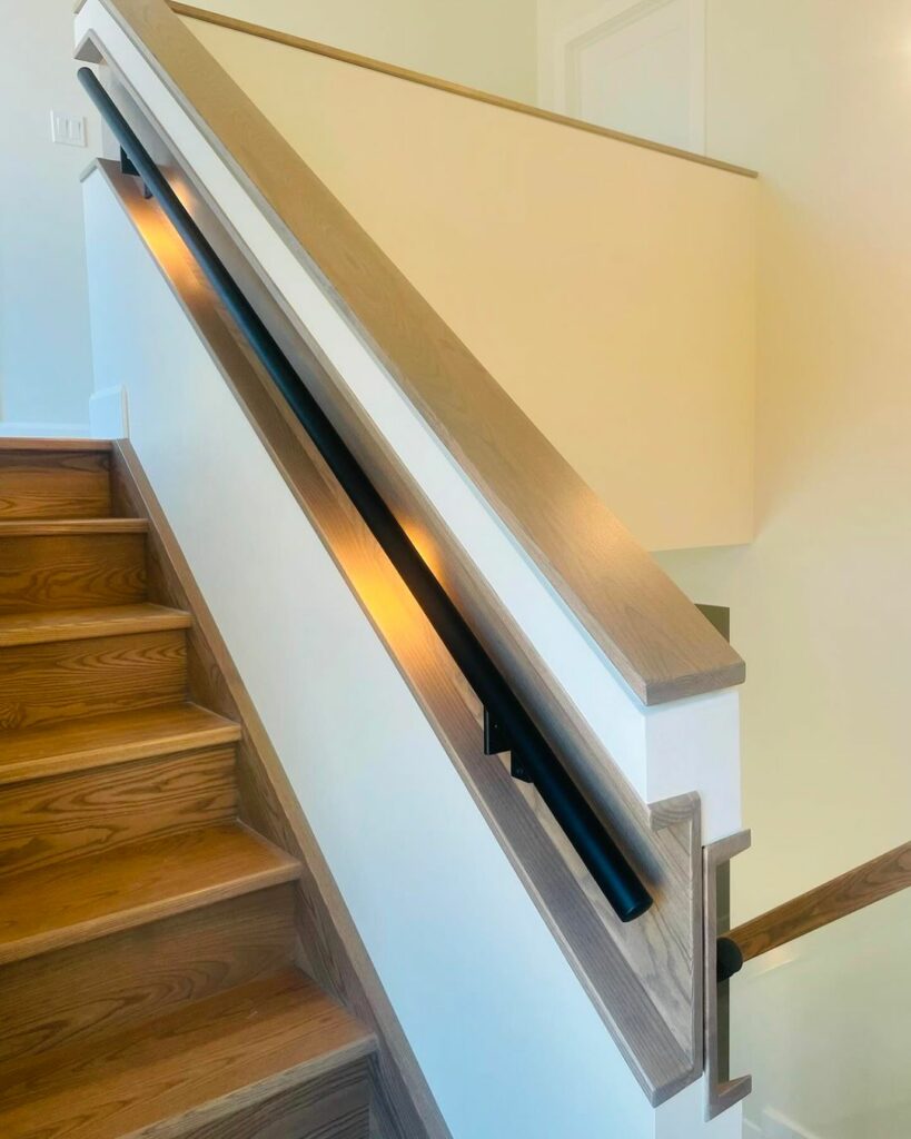 LED-illuminated satin black rail set into architectural cutouts for modern staircase design.